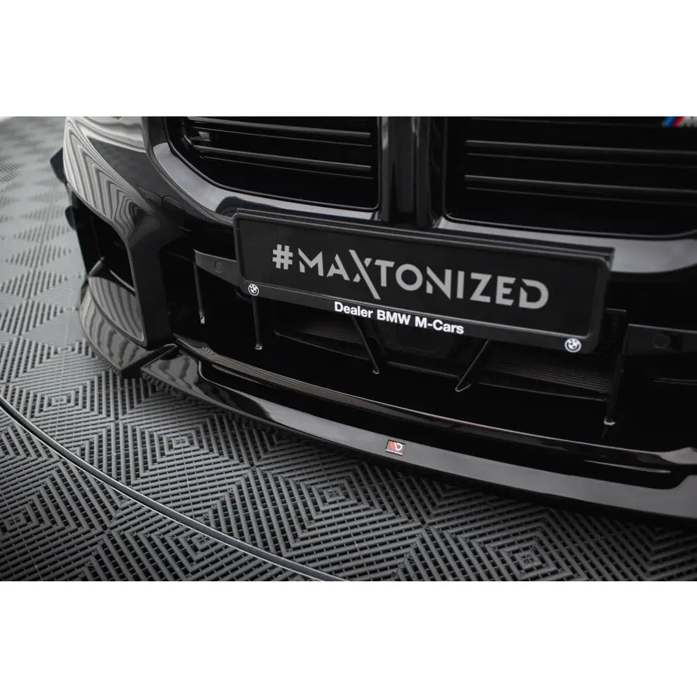Spoiler til BMW M2 G87 V5 i sort blank plast, sett forfra under grill med #MAXTONIZED på skiltholder.