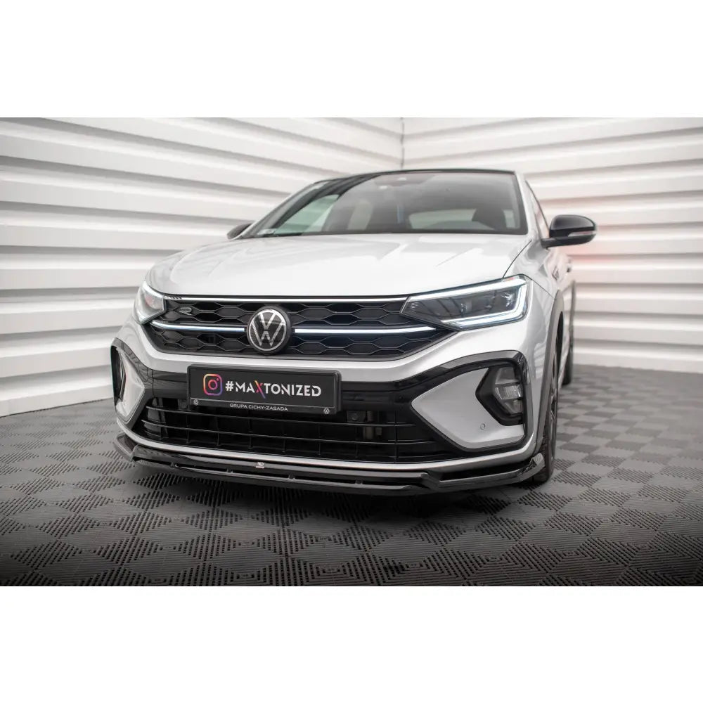 Front splitter på Volkswagen Taigo R-Line Mk1 med svart grill og sportystøtfanger mot nøytral bakgrunn.