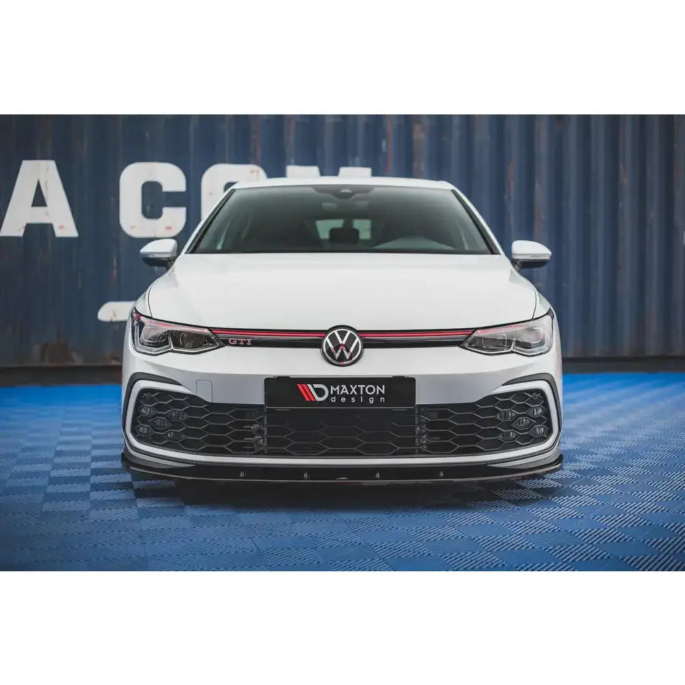 Front splitter på VW Golf 8 GTI med sort grill, rød stripe og Maxton Design-logo på skiltet.