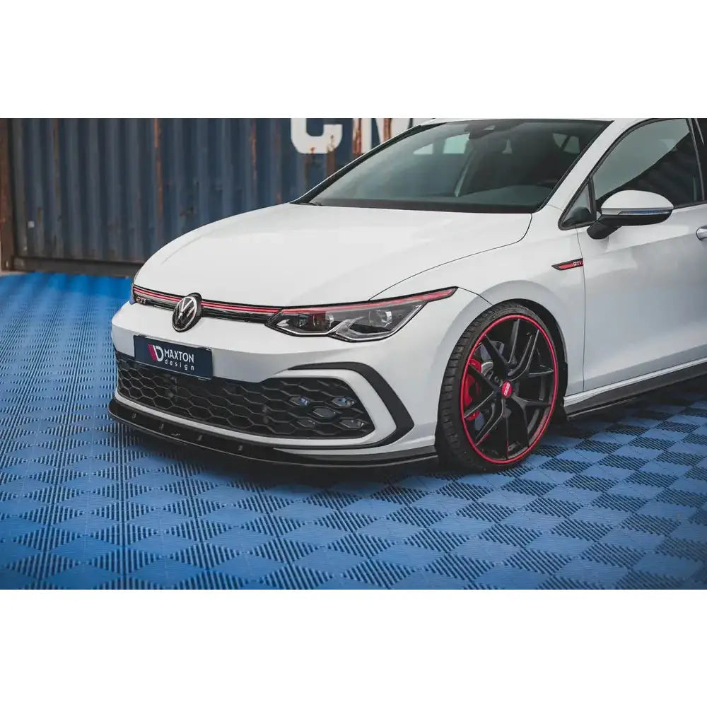 Frontspoiler VW Golf 8 GTI sett fra venstre front med sorte felger og røde detaljer på felgene.