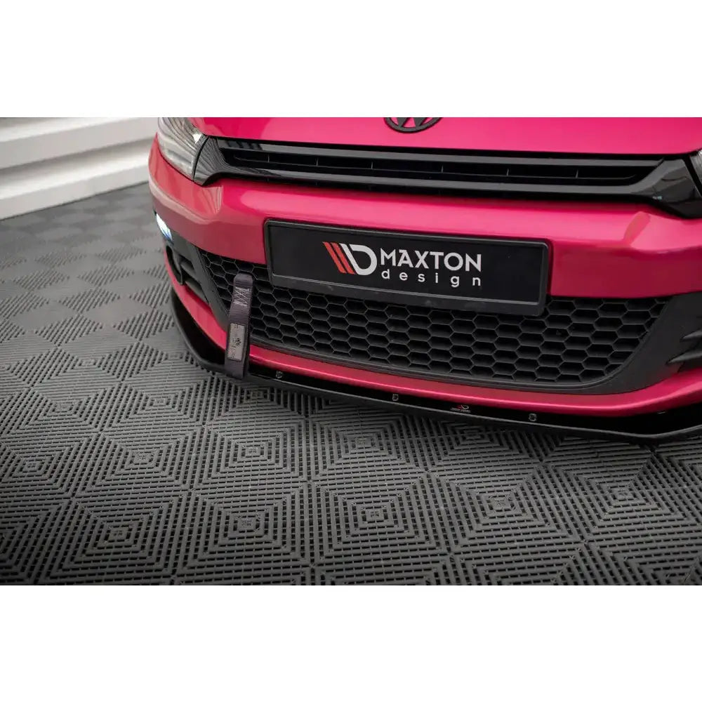 Front splitter på rød VW Scirocco med sort grill, Maxton Design-skilt og rød taustropp foran.