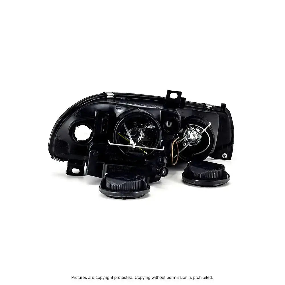 Headlamp bakside av Alfa Romeo 156 frontlykter med synlige sokler, ledninger og to løse dekklokk.