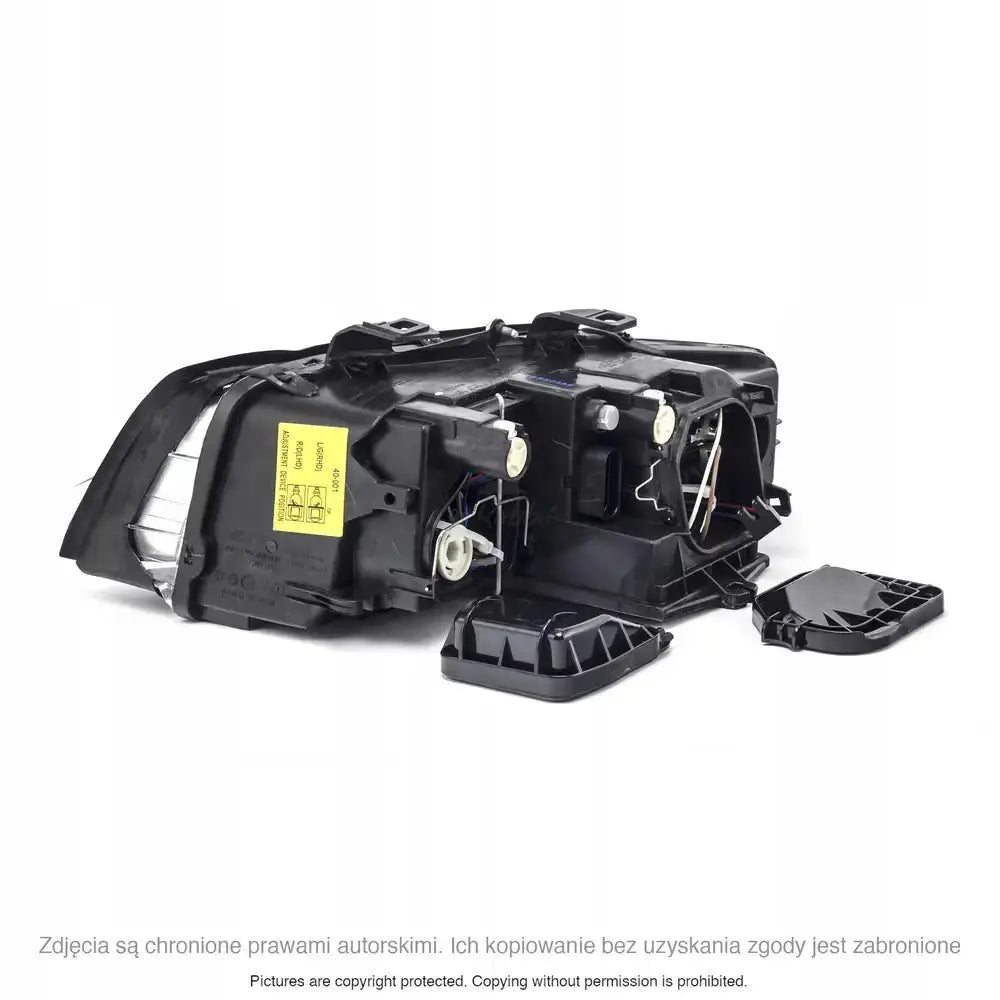 Hovedlys Audi A4 B6 bakside med synlige tekniske detaljer, kabler og avtakbart deksel ved siden av.