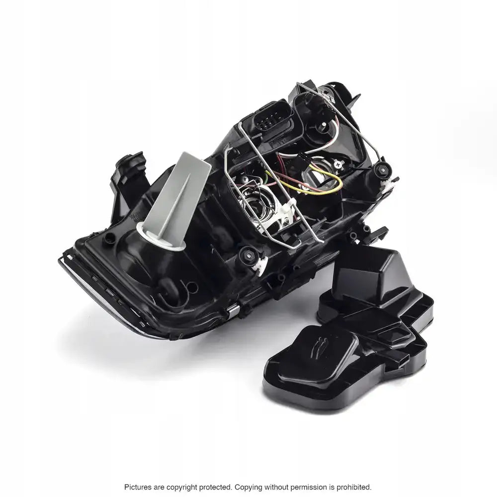 Headlamp Audi A6 C5 frontlykt med åpent lokk, synlige ledninger og komponenter mot hvit bakgrunn.