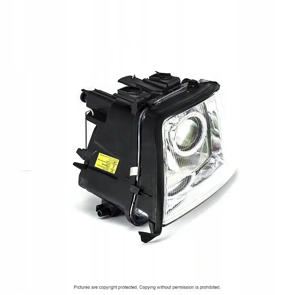 Headlights Audi A6 C5 99-01 vist fra skrå vinkel med reflektor, pære og gul informasjonsetikett.