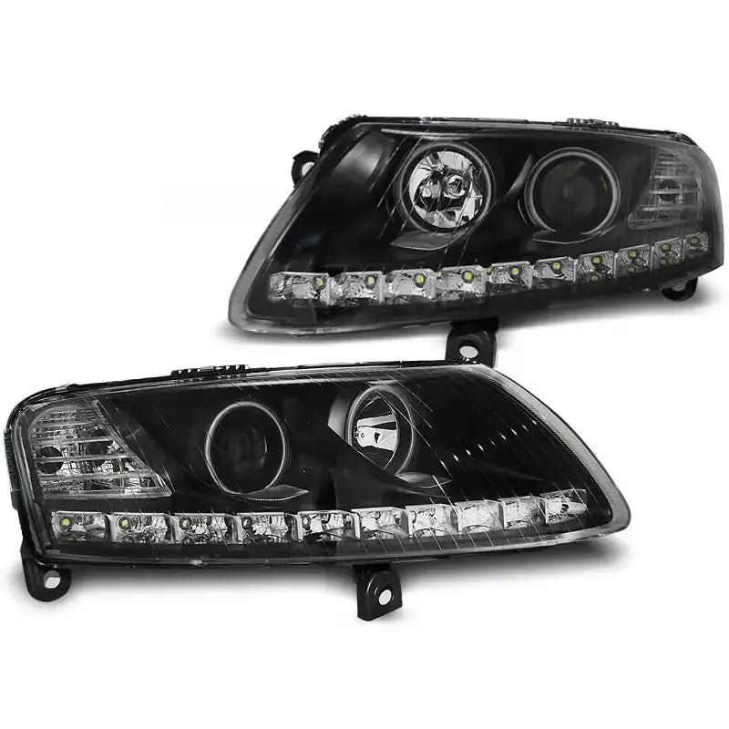 Hovedlykter Audi A6 C6 Angel Eyes LED Black, to svarte lykter med klare linser og LED-lys sett skrått forfra.