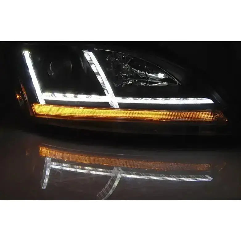 Headlights Audi TT 06-10 8J Black med hvit LED-strip og oransje LED-lys, sett fra skrå vinkel.