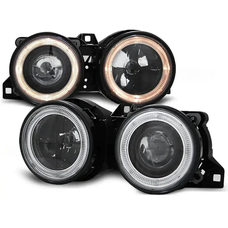 Hovedlykter Bmw E30 Angel Eyes Black med to hvite og to oransje LED-ringer, sett fra skrå vinkel.