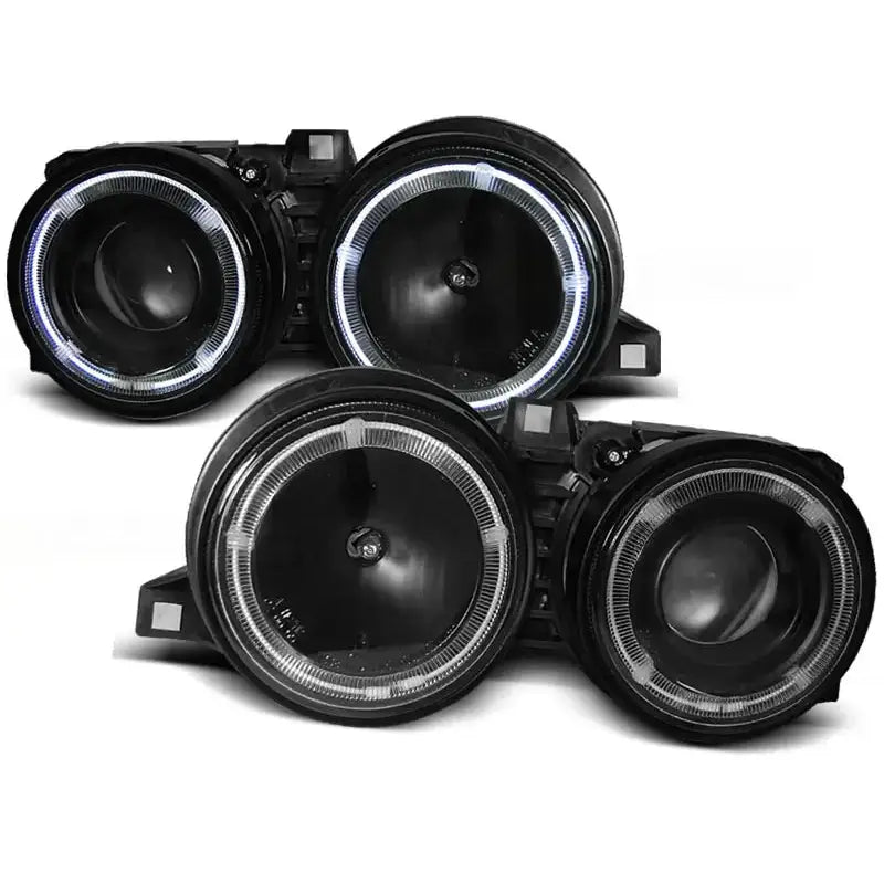 Frontlykter Bmw E30 Angel Eyes Black med runde LED-lysringer, sett fra skrå vinkel mot hvit bakgrunn.