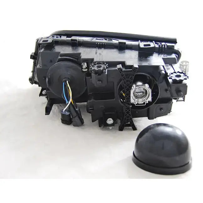 Hovedlykter Bmw E46 sett bakfra med ledninger, koblinger og rund avtagbar kapsel synlig i plast.
