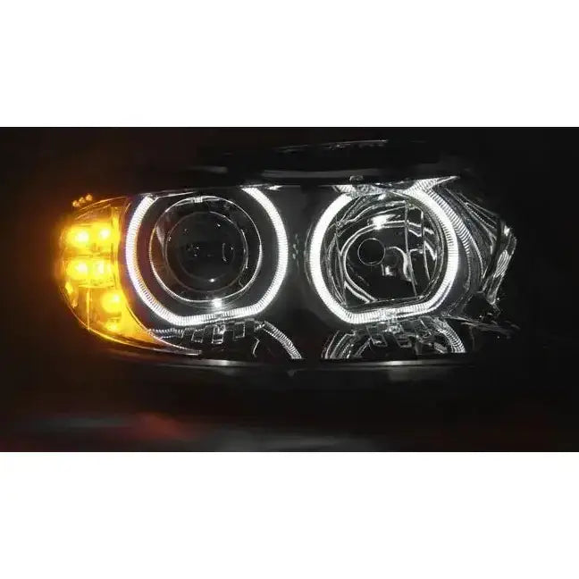 Headlights Bmw E90/E91 LED Angel Eyes sett forfra med hvite lyssirkler og gule LED-lys i sort ramme.