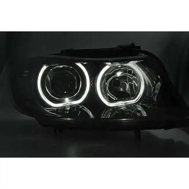 Headlamp Bmw E90/E91 sort LED angel eyes sett forfra med hvite lysringer i mørkt miljø.