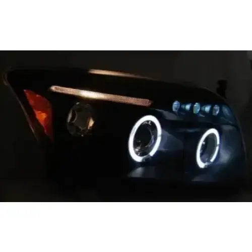 Hovedlys Dodge CALIBER Angel Eyes Black med to LED-ringer og oransje sidefelt, sett skrått forfra.