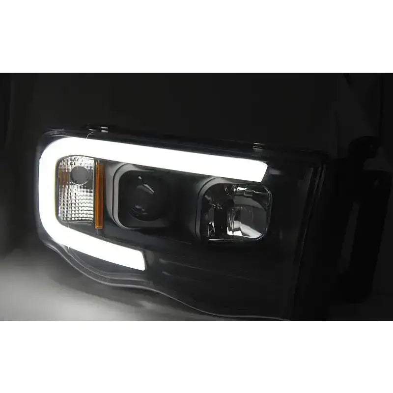 Hovedlys Dodge Ram 02-06 Tube Light Black med hvit LED-ramme sett forfra i mørkt miljø.