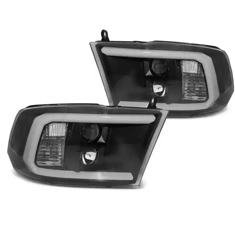 Frontlykter Dodge Ram 09-18 Tube Light Black med hvit LED-ramme i sort og klart plast, sett fra skrå vinkel.