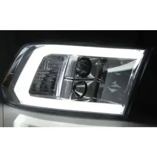 Hovedlys Dodge Ram 09-18 Tube Light Chrome med klart glass og LED-ramme sett forfra mot mørk bakgrunn.