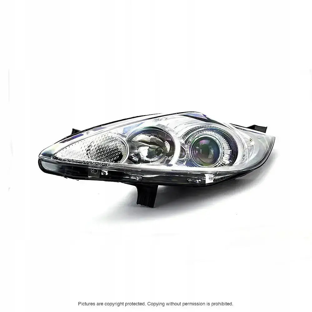 Hovedlykter Ford Fiesta 08-13 i klart glass og sort plast sett fra skrå forside mot hvit bakgrunn.