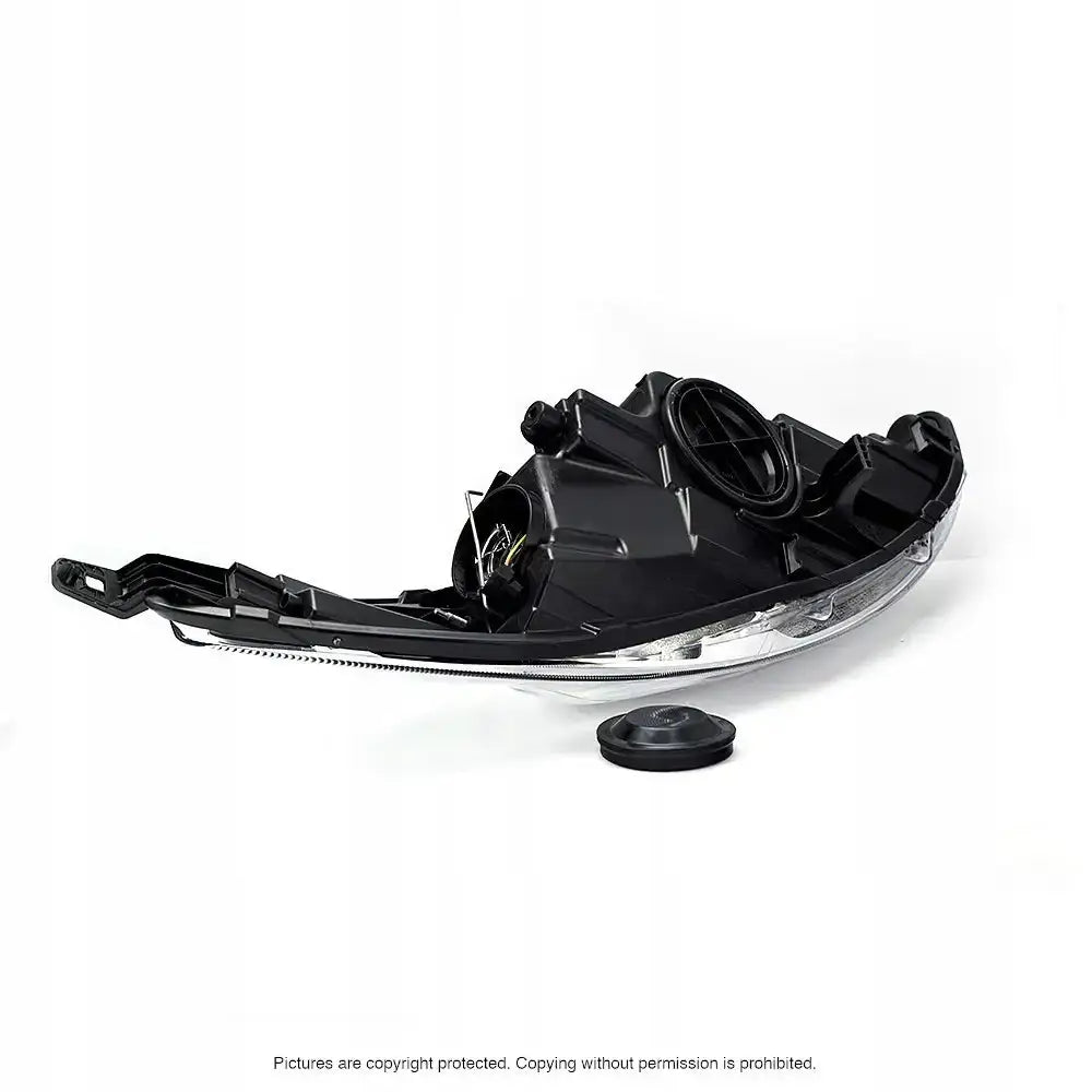 Frontlykter Ford Fiesta 08-13 vist bakfra med avtagbart deksel på hvitt underlag.