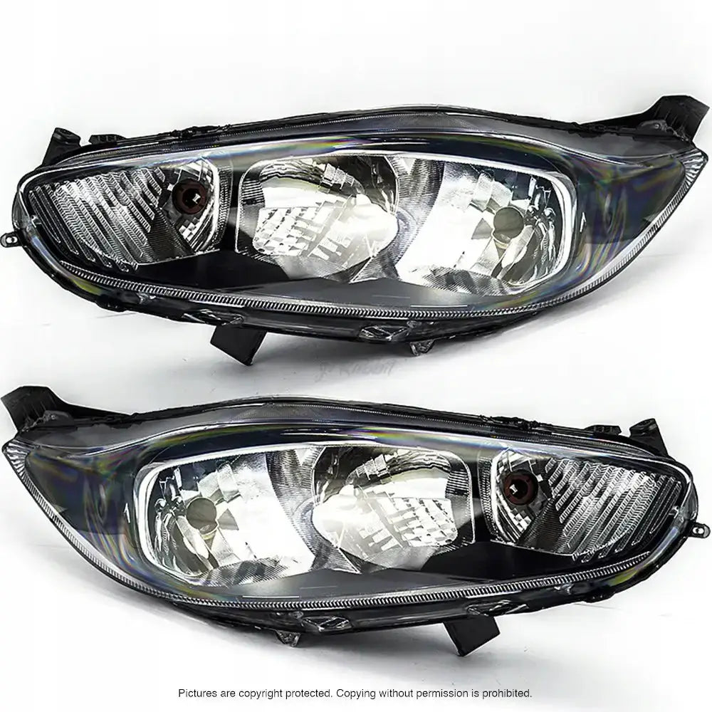 Frontlykter Ford Fiesta 13-17 med klare glass og sølvfargede reflekser vist skrått forfra på hvit bakgrunn.