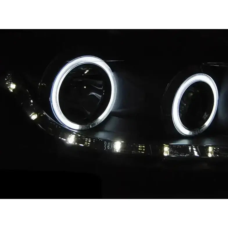 Headlamp Ford Focus II Angel Eyes CCFL Black med hvite LED-ringer og ekstra LED-pærer vist forfra i mørket.