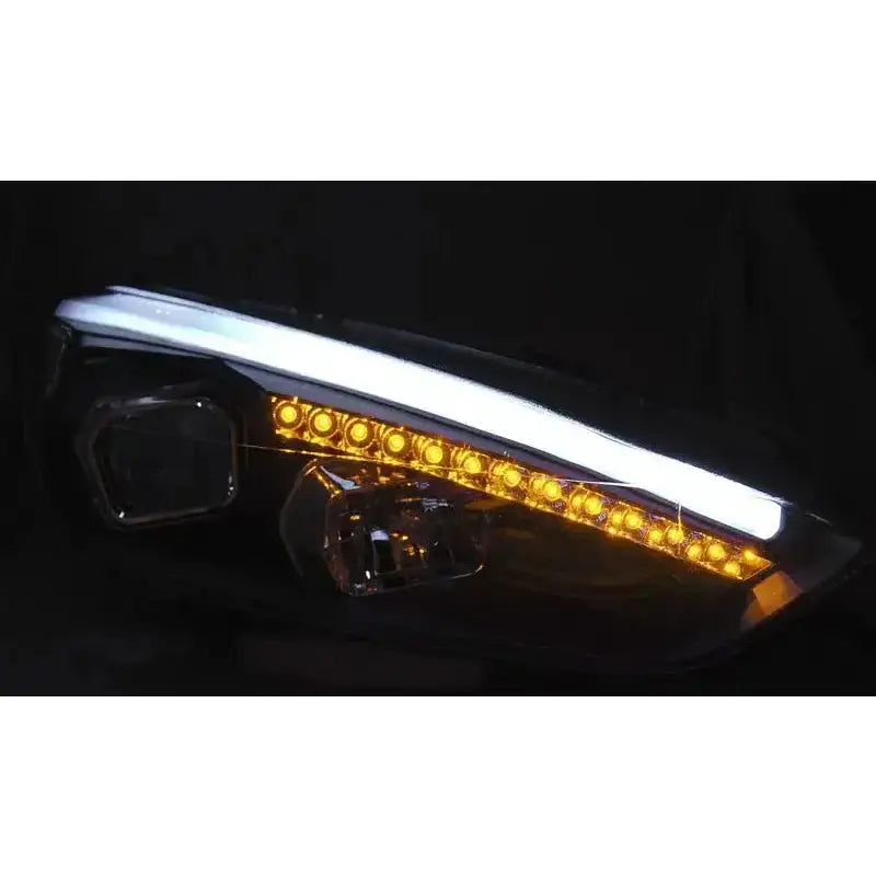 Headlights Ford Focus Mk3 15- med sorte detaljer, gule LED-lys og hvit DRL, sett fra skrå front.