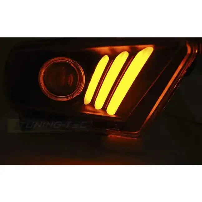 Headlamp Ford Mustang V 10-13 med tre gule LED-striper og rund linse, vist i mørkt miljø.