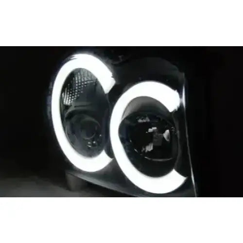 Hovedlys Jeep Grand Cherokee 05-08 med svarte detaljer og LED-ringer, sett skrått forfra mot mørk bakgrunn.