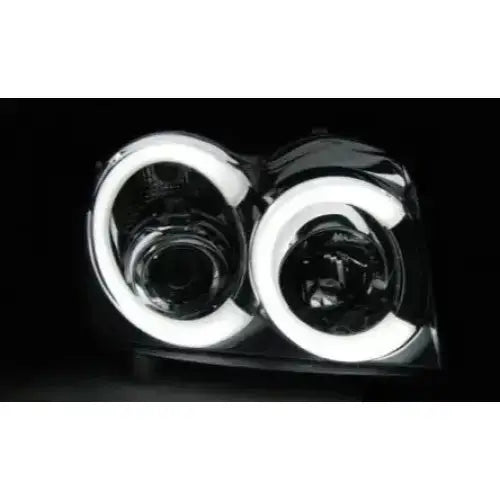 Hovedlykter Jeep Grand Cherokee 05-08 Chrome Tube Light med runde LED-lys, sett forfra mot mørk bakgrunn.