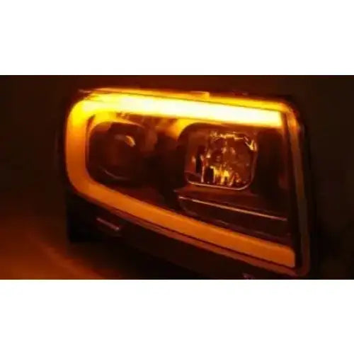 Hovedlys Jeep Grand Cherokee 11-13 med oransje LED-lysramme og svarte detaljer sett fra skrå front.