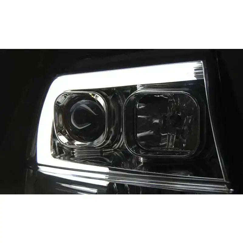 Headlights Jeep Grand Cherokee 99-05 Tube Light Chrome med klart glass og LED-lysbånd, nærbilde mot svart bakgrunn.