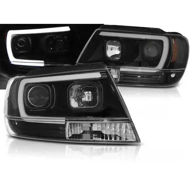 Frontlykter Jeep Grand Cherokee 99-05 Tube Light Black med LED-lysstriper og klare linser, skrå forside.