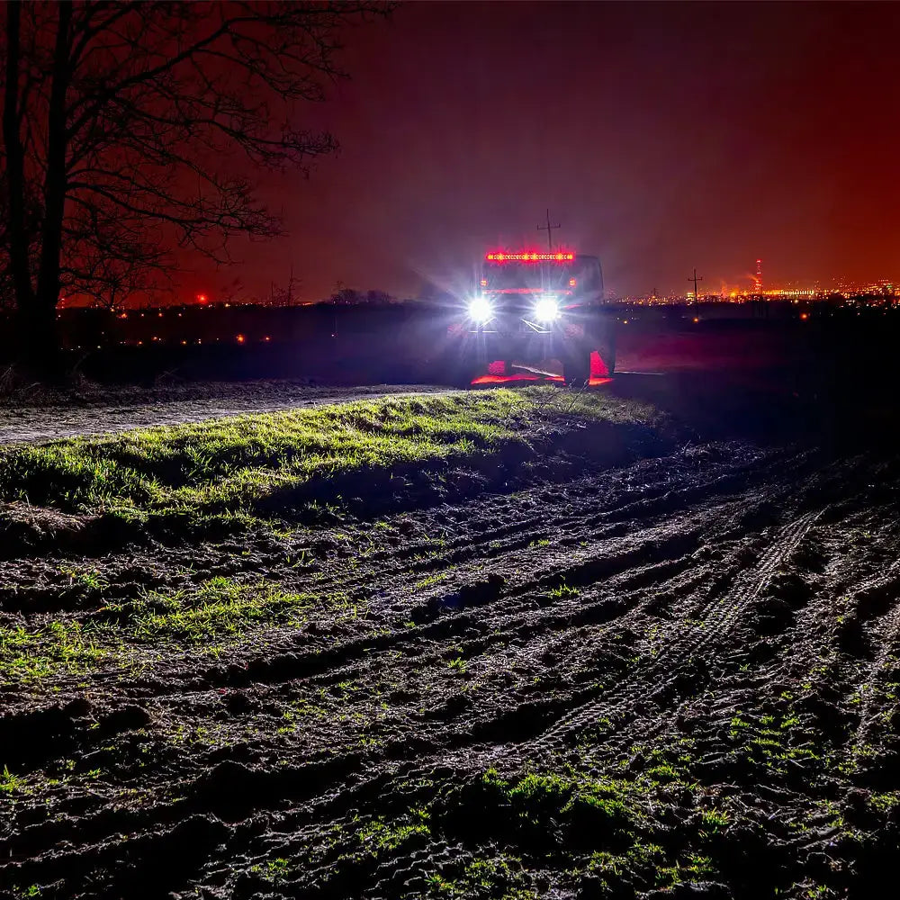 Frontlykter LED Ring Truck Lite Jeep Wrangler JK lyser opp foran kjøretøyet på en mørk jordvei.