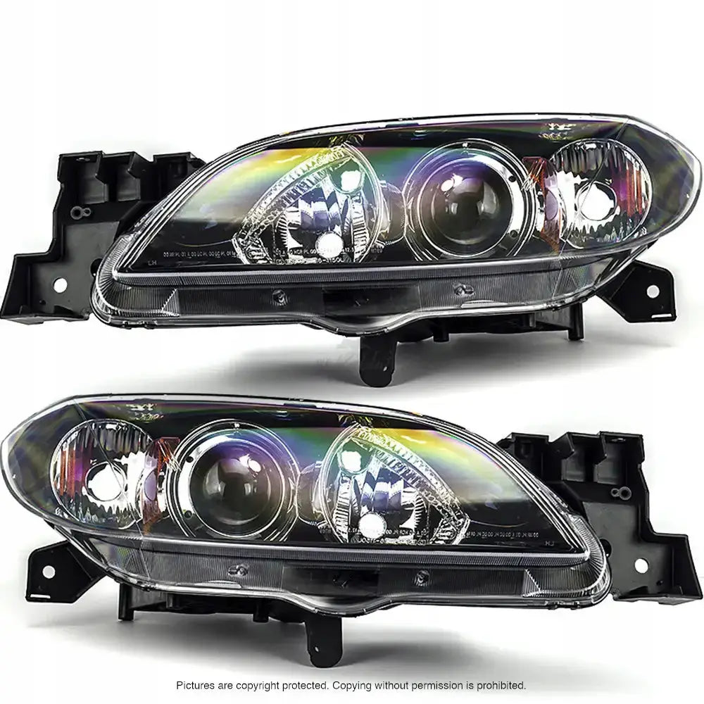 Frontlykter Mazda 3 03-09 sedan, to hovedlykter med klar plastfront og svarte rammer, sett fra skrå vinkel.