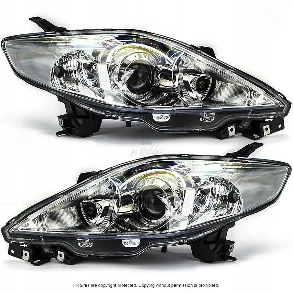 Frontlykter Mazda 5 CR19 04-10 i klart plast og metall, sett fra skrå vinkel med sorte festebraketter.