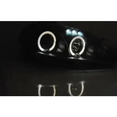 Hovedlykter Mazda MX5 01-05 Angel Eyes Black med LED-lysringer, sett skrått forfra på mørk bakgrunn.