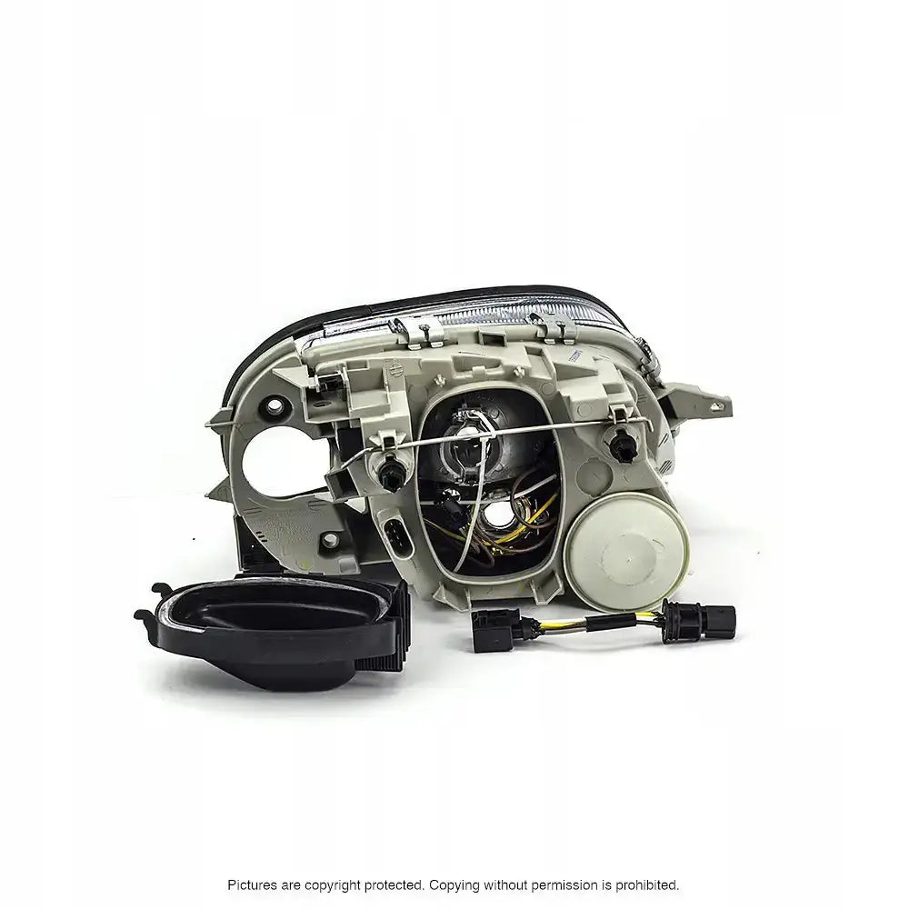 Headlamp bakside av Mercedes SLK R170 billykt i grå plast med ledninger og løst deksel foran.