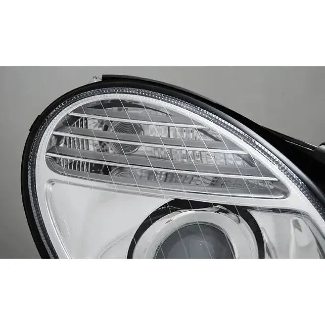 Hovedlykter Mercedes W211 E-Klasse med klart glass og sølvfarget innside, detaljerte reflektorer.