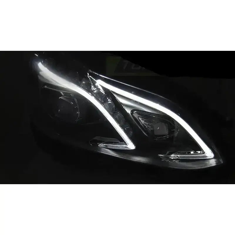 Hovedlykter Mercedes W212 13-16 Black LED DRL med lysstripe sett skrått forfra mot svart bakgrunn.