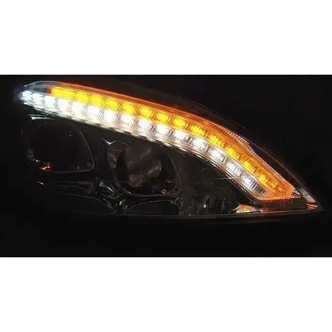 Headlamp Mercedes W221 Daylight HID Black LED-frontlykt med oransje og hvit lysstripe tent mot mørk bakgrunn.