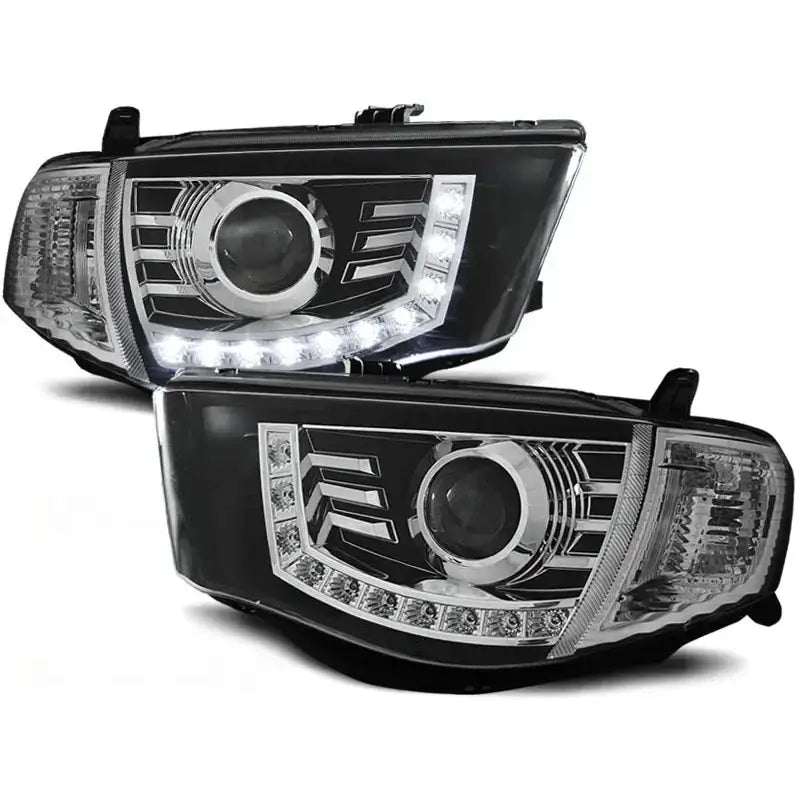 Hovedlykter Mitsubishi L200 06-10 Daylight Black med LED-lysrekker og kromdetaljer, sett i skrå vinkel.