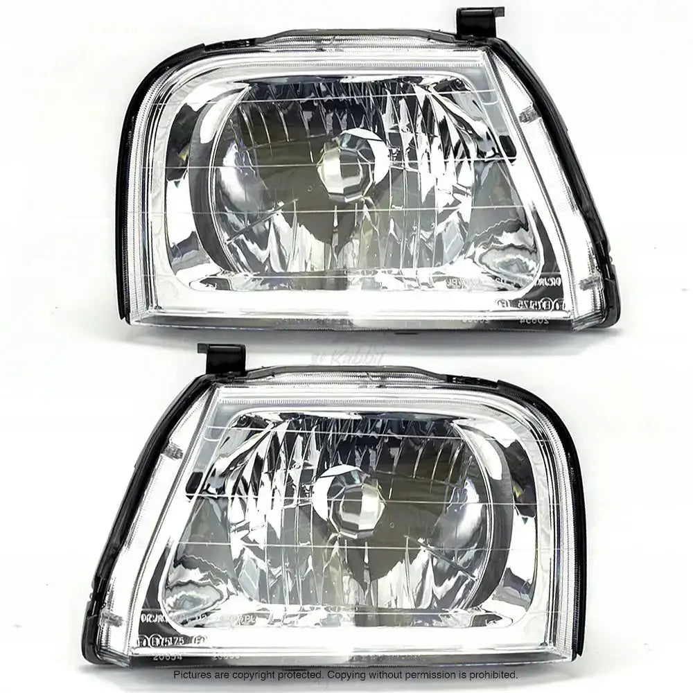Frontlykter Mitsubishi L200 96-05 H4 sett fra forsiden med klare linser og sorte detaljer.