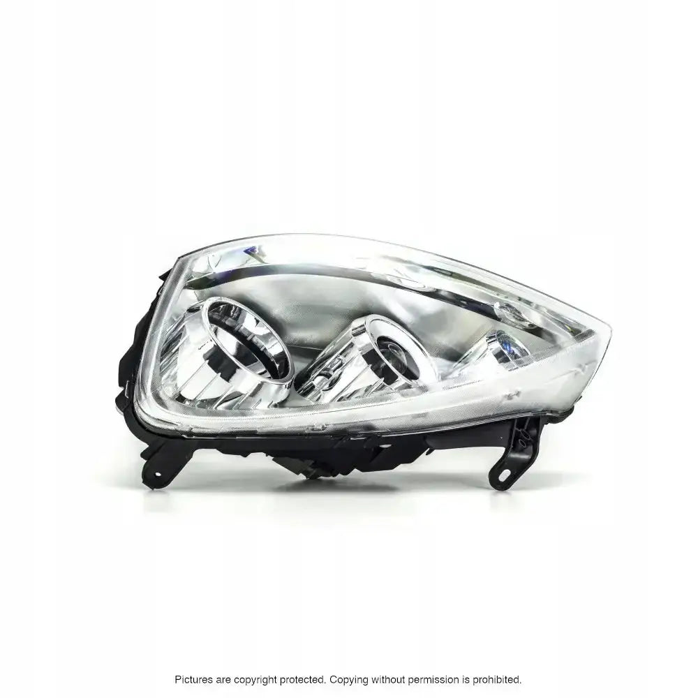 Frontlykter Opel Corsa C 03-10 med klart glass og sølvreflektor sett skrått forfra mot hvit bakgrunn.