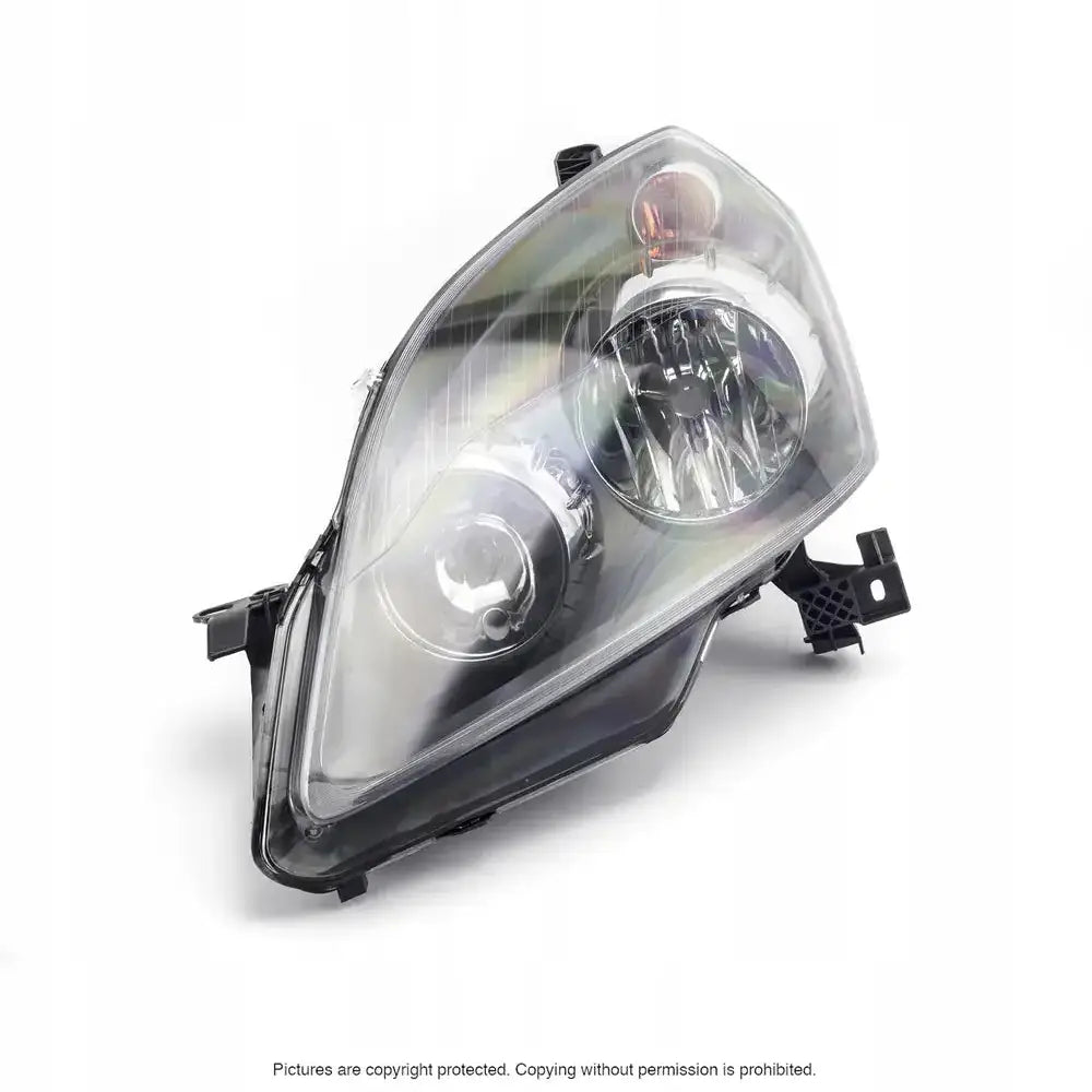 Headlamp Opel Zafira B 05-08 med synlige reflektorer og pærer bak klar plast, sett fra skrå frontvinkel.