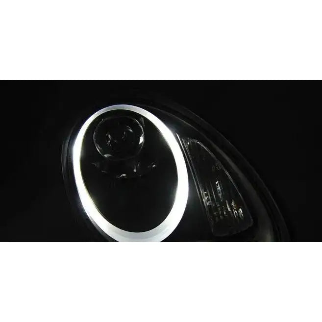 Hovedlys Porsche Boxster CAYMAN 987 HID Black med hvit LED-lysring, fotografert i mørket.