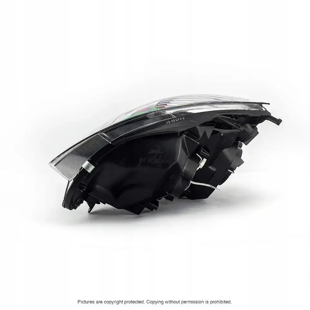 Hovedlys Renault Clio II frontlykt i sort og klar plast, sidevisning med detaljer på bakside og underdel.