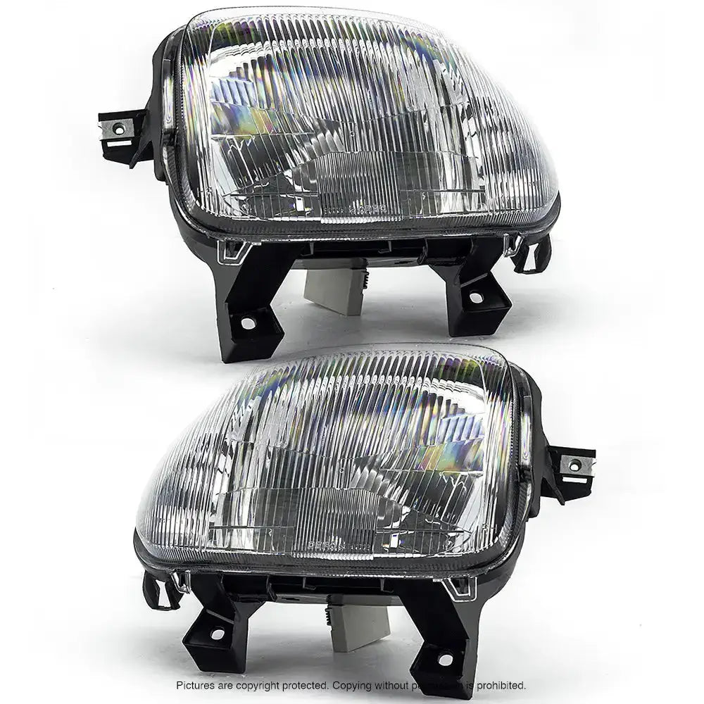 Hovedlykter Renault Clio II 98-01 i klar plast med sorte fester, sett skrått forfra mot hvit bakgrunn.