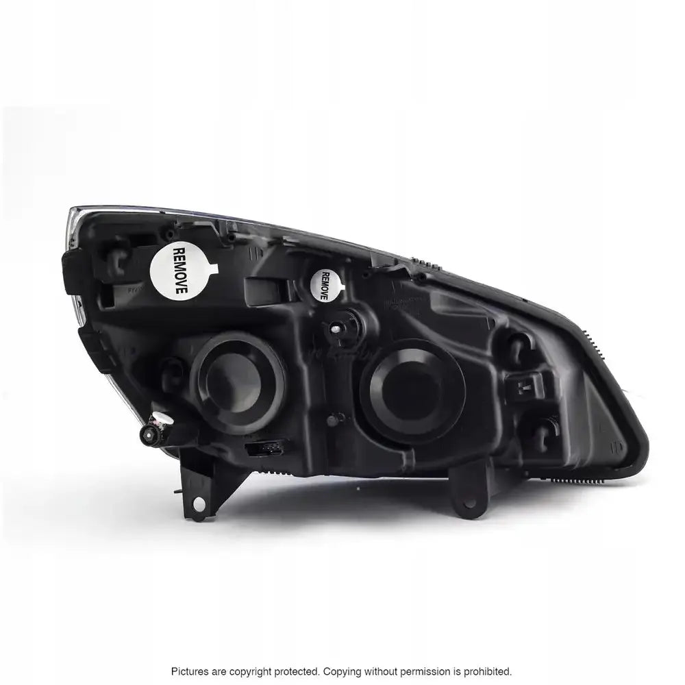 Frontlykter Renault Scenic 03-09 sett bakfra med svarte hus, to runde luker og «REMOVE»-klistremerke.