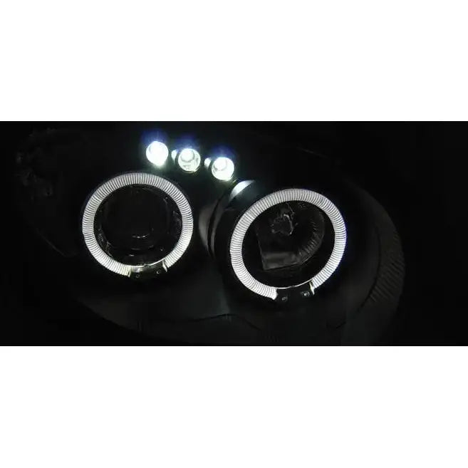 Hovedlys Subaru Impreza II GD Angel Eyes Black med hvite LED-ringer og tre LED-lys, sett forfra i mørket.