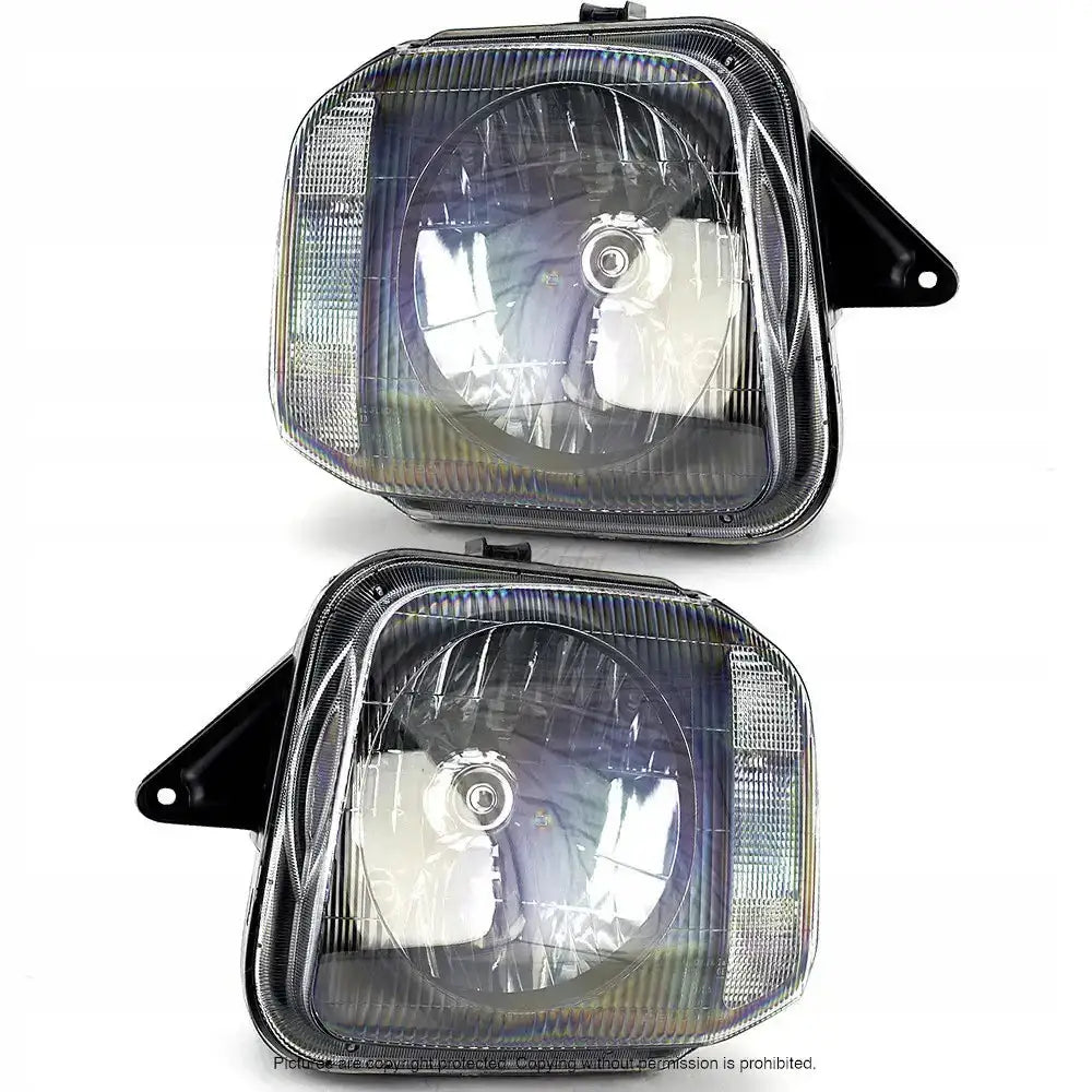 Frontlykter Suzuki Jimny 98-05 med klart glass og svarte detaljer, sett fra skrå vinkel mot hvit bakgrunn.