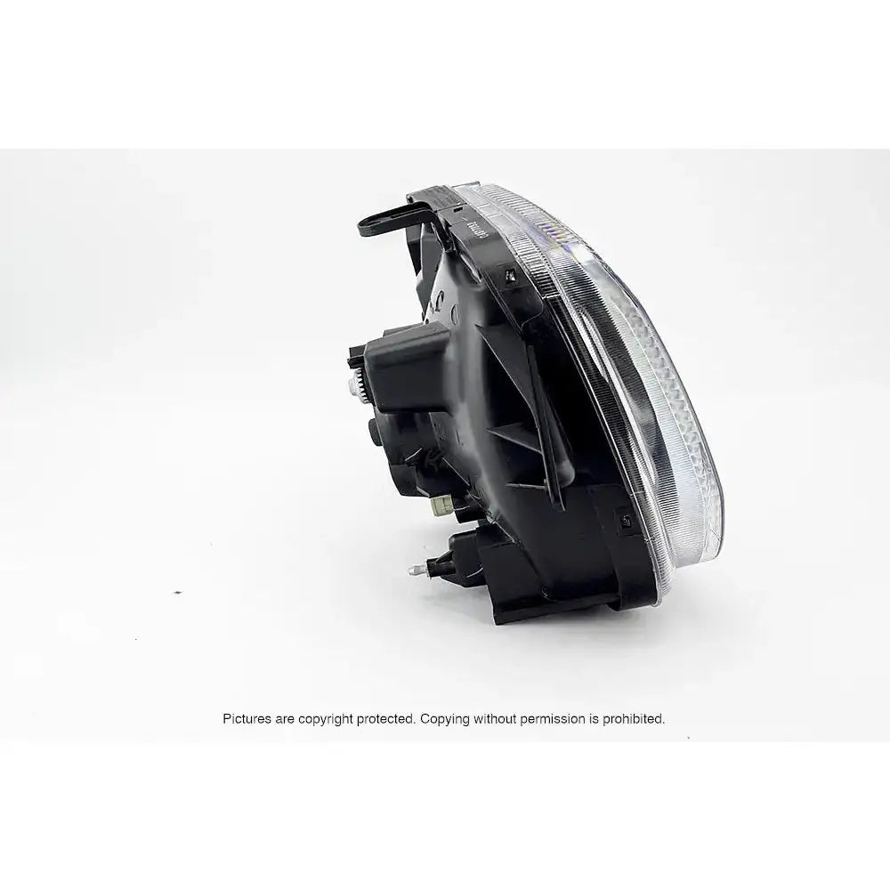 Hovedlys Suzuki Jimny 98-05 H4 med klart glass og svart hus, sett fra skrå bakvinkel.